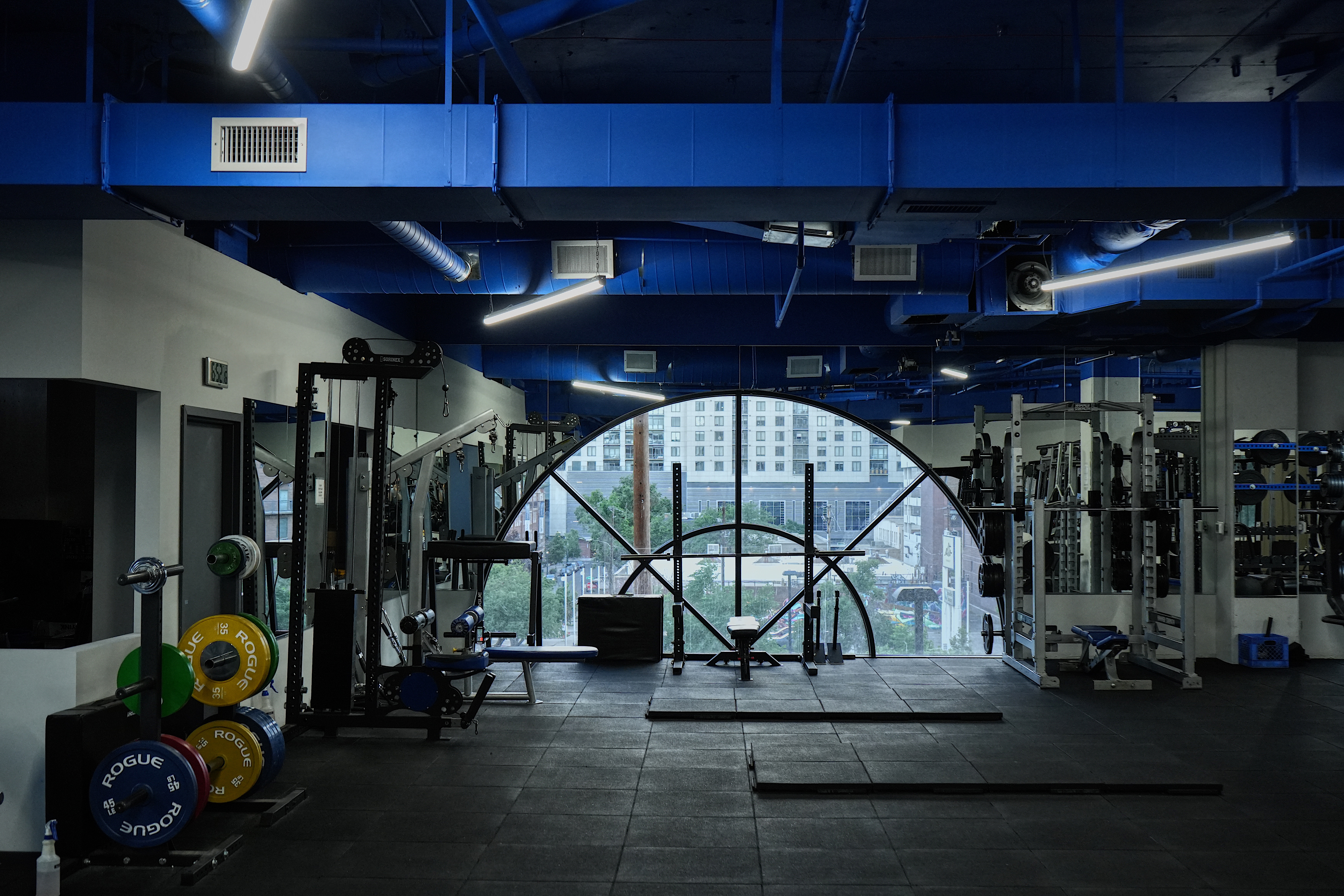 Summit Strong gym interior with dramatic arched window overlooking the Denver skyline