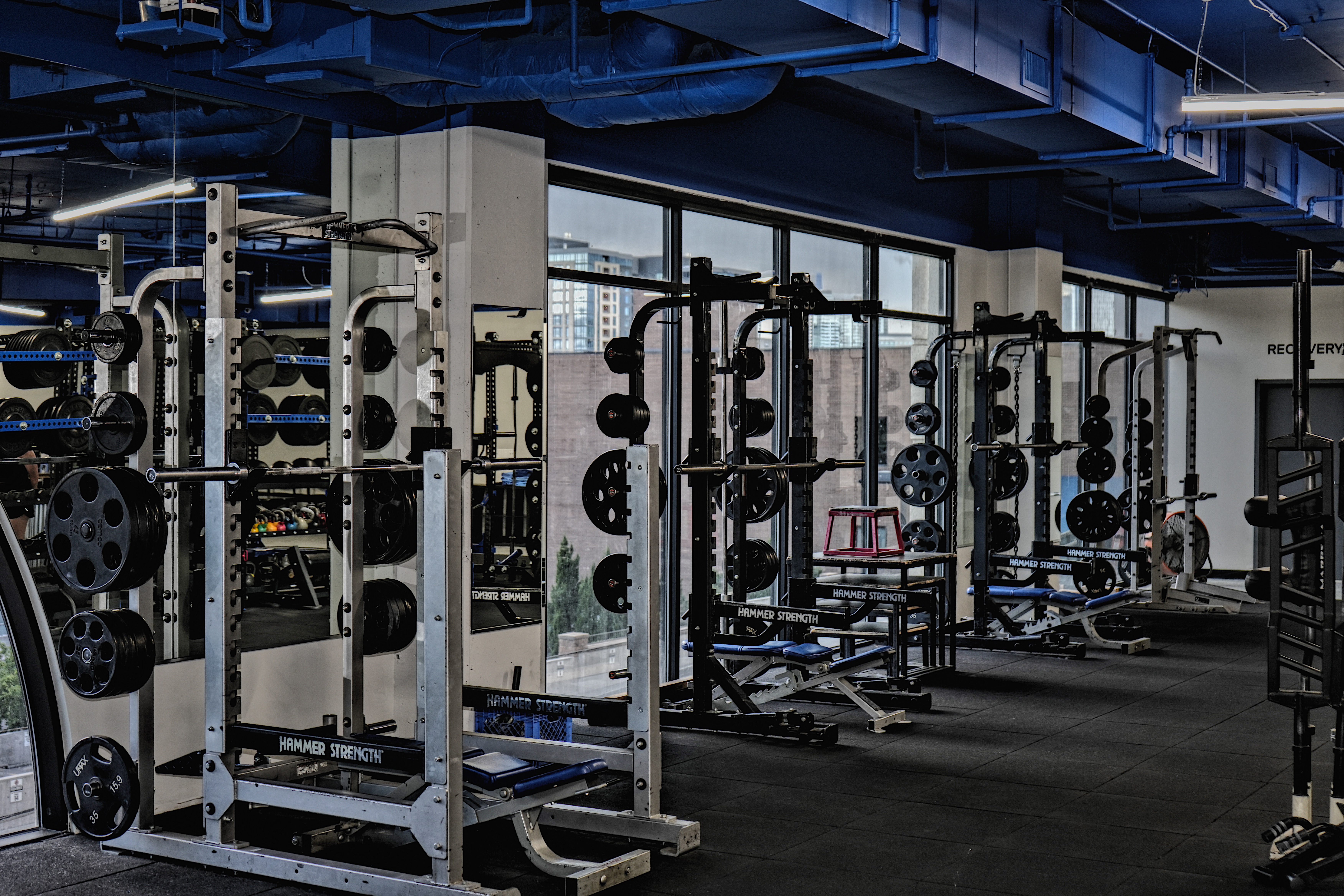 Summit Strong squat racks with panoramic Denver skyline view through arched windows